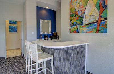 2 Queen Bed Suite at Alister Square Inn with white furniture, blue decor, and natural lighting